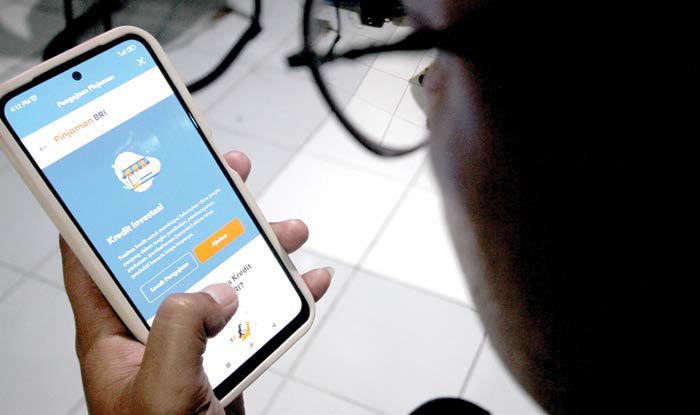 SEMAKIN MUDAH: Seorang warga mengakses layanan perbankan melalui ponsel kemarin siang