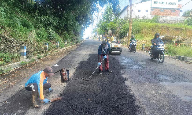 INFRASTRUKTUR: Pekerja dari DPUBM Kabupaten Malang menambal beberapa titik berlubang di Jalan Jurang Akhir, Desa Sidorahayu, Kecamatan Wagir