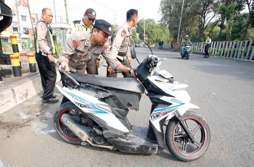 AKIBAT TAK SABAR: Polisi memindahkan Honda Beat milik M. Romli setelah disambar KA Sri Tanjung kemarin.