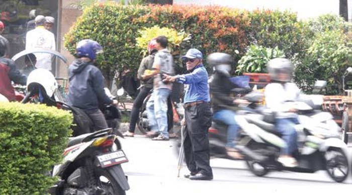 MASUK KATEGORI RENTAN: Seorang supeltas mengatur lalu lalang kendaraan di simpang tiga Jalan Trunojoyo kemarin