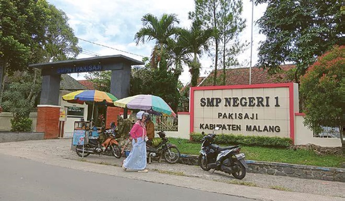 TINGKAT KAN KUA LITA S: Seorang melintas di depan gerbang SMPN 1 Pakisaji pada Jumat lalu (30/5). Penetapan sekolah unggulan diprioritaskan SMP terlebih dahulu.