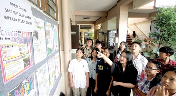 BUKA SATU ROMBEL: Siswa SMP Katolik Mardi Wiyata membaca informasi terkait SPMB Online 2025.