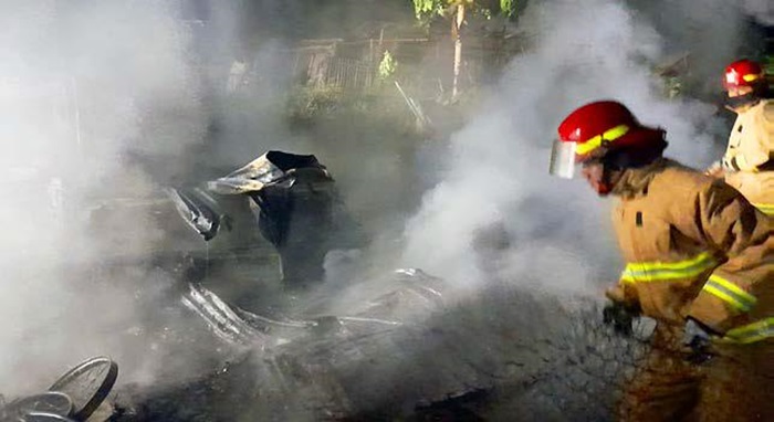 GERAK CEPAT: Dua personel dari Damkar Kabupaten Malang memadamkan kobaran api yang membakar lahan dan gudang rongsokan di Desa Mulyoagung, Kecamatan Dau pada Jumat malam (30/5).