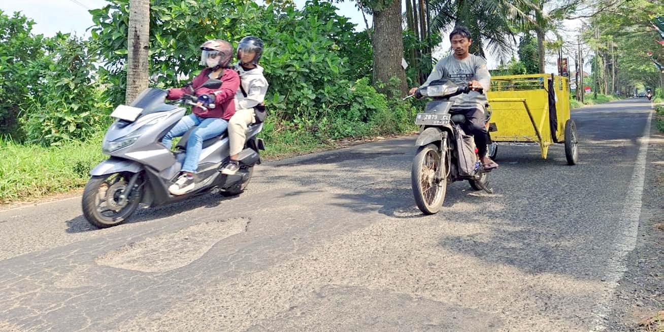 HATI-HATI: Pengendara sepeda motor menghindari lubang di Jalan Raya Tlogowaru kemarin (7/6) . Pemkot Malang berencana memperbaiki jalan di sana menggunakan DBHCHT tahun ini.