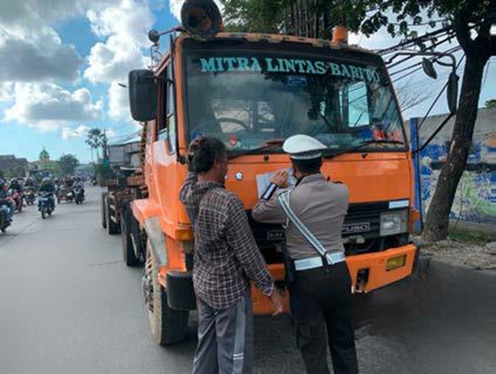 DITERTIBKAN: Petugas Satlantas Polres Pelabuhan Tanjung Perak menilang truk yang melanggar aturan jam melintas di Jalan Kalianak.