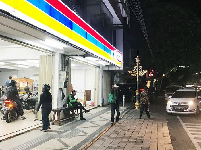 PAKAI ROMPI: Seorang juru parkir mengatur kendaraan di depan minimarket Jalan Basuki Rahmat, Kecamatan Klojen, Kota Malang kemarin.