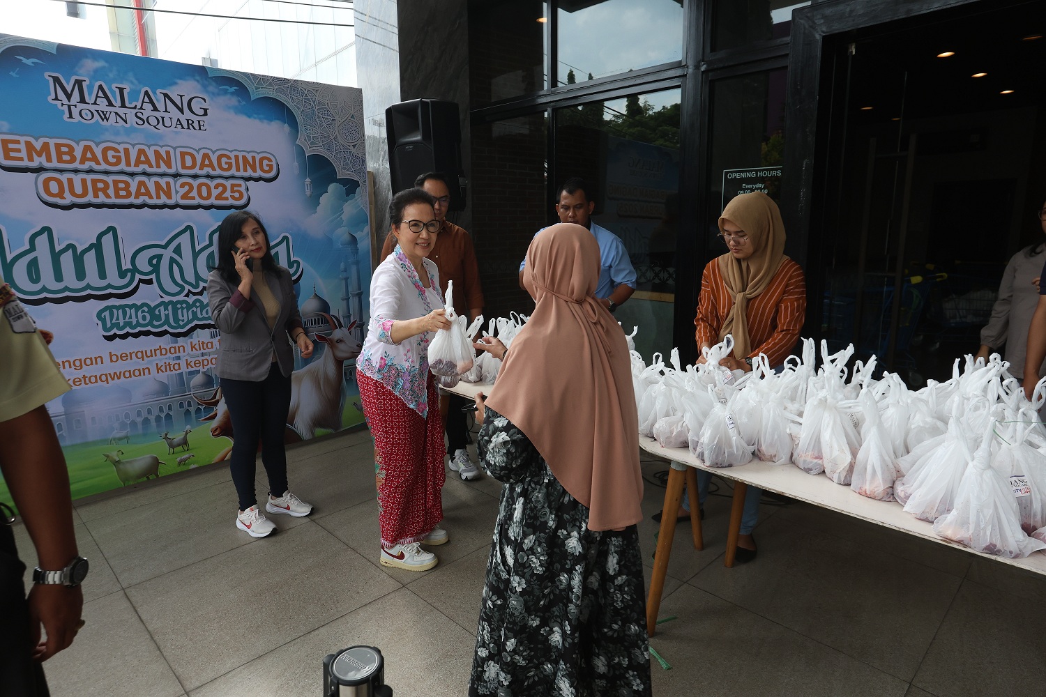 Mall Director Malang Town Square Fifi Trisjanti (baju putih) membagikan daging kurban kepada penerima. (Darmono/Radar Malang)