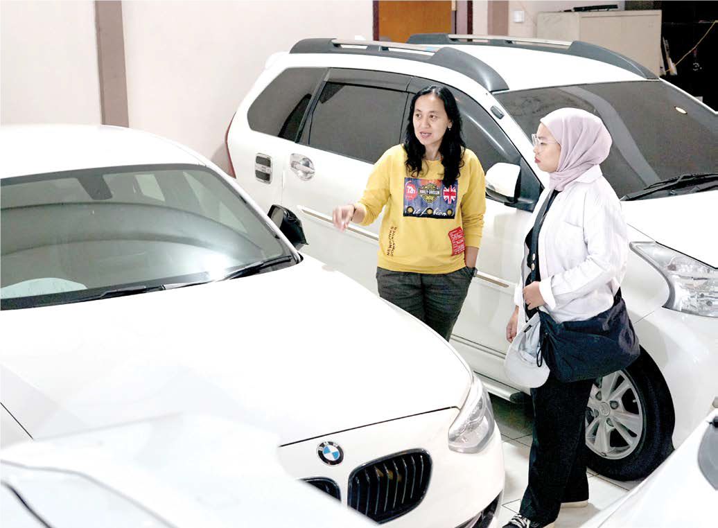 PENJUALAN MENURUN: Seorang admin diler mobil bekas di kawasan Blimbing melayani calon pembeli kemarin.