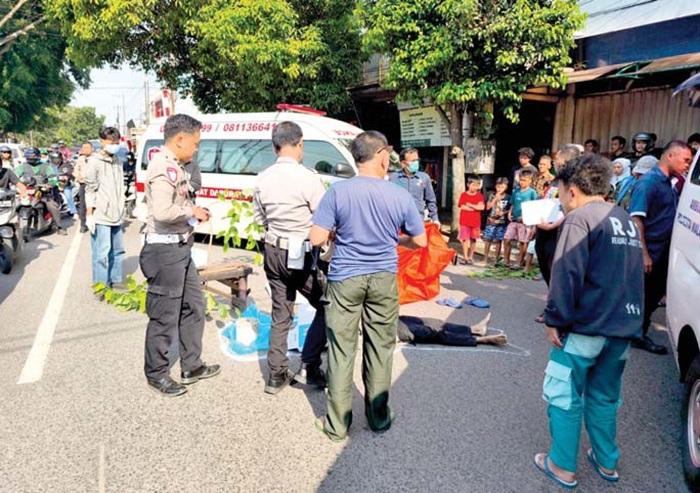 DIDUGA BUNUH DIRI: Polisi mengevakuasi jenazah Anggit Kurniawan Syukron Akbar yang tewas setelah dilindas truk kemarin.