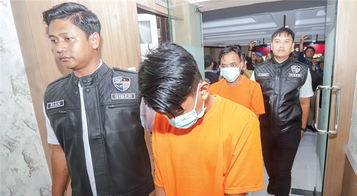 OTAK UTAMA: Dua pengelola grup facebok Gay Khusus Surabaya memakai baju tahanan dan digiring ke Polres Pelabuhan Tanjung Perak kemarin.