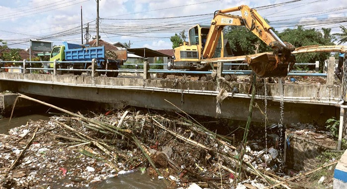 JAGA LINGKUNGAN: Satu unit alat berat diterjunkan untuk mengeruk tumpukan sampah bambu di Kali Sukun, Desa Karangduren, Kecamatan Pakisaji kemarin.