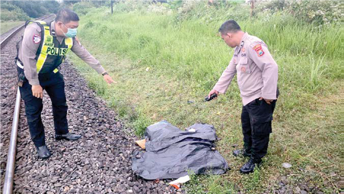 TANPA IDENTITAS: Dua personel Polsek Sukun mengevakuasi jenazah pria yang tewas setelah tertemper KA Penataran kemarin.