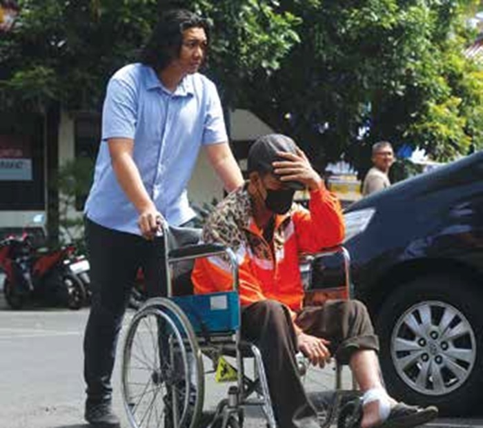 AJUKAN PENANGGUHAN: Pemilik home industry trobas, Yudi Wahono, 56, didorong menggunakan kursi roda di halaman Mapolres Malang.