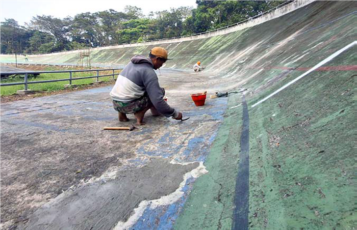 DIKEBUT: Beberapa bagian lintasan sepeda di Velodrome yang mengelupas ikut ditambal sebelum dicat.