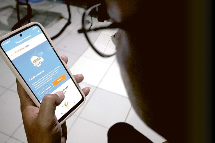 LAYANAN DIGITAL: Seorang nasabah mengakses informasi kredit perbankan lewat ponsel pintarnya kemarin.