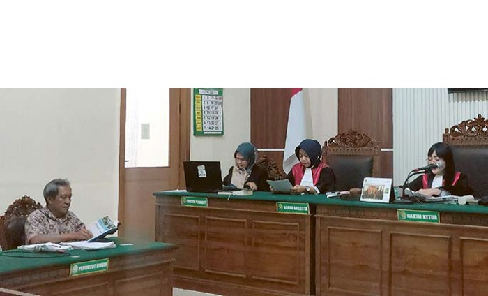 BELUM LUNAS: Wardojo (kiri) memeriksa berkas gugatan dalam sidang di Pengadilan Negeri Surabaya kemarin (23/6).