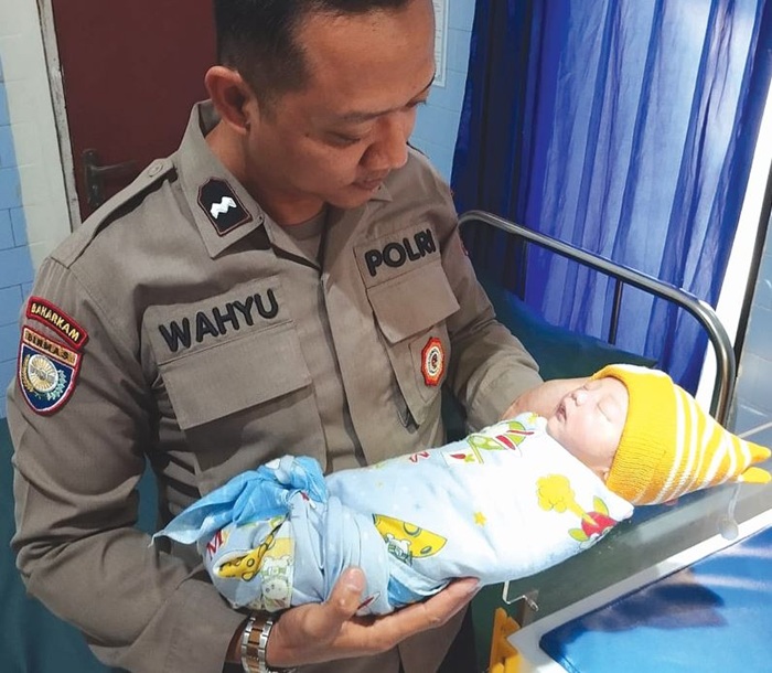 LAHIR TAK DIHARAPKAN: Personel Polsek Bululawang menggendong bayi yang diduga dibuang oleh orang tuanya di Dusun Sidomakmur, Desa Lumbangsari, Bululawang kemarin (23/6).