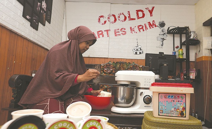 SIAP LAYANI JUMLAH BESAR: Seorang penjual es krim di Dusun Damean, Desa Tamanharjo, Kecamatan Singosari melayani pelanggannya kemarin.