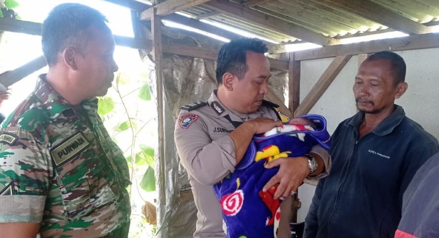 PENEMUAN BAYI: Petugas dari Polsek Gondanglegi menggendong bayi yang ditemukan warga tergeletak di lapak ikan Jalan Raya Mbureng, Desa Sukosari, Kecamatan Gondanglegi kemarin (27/6).
