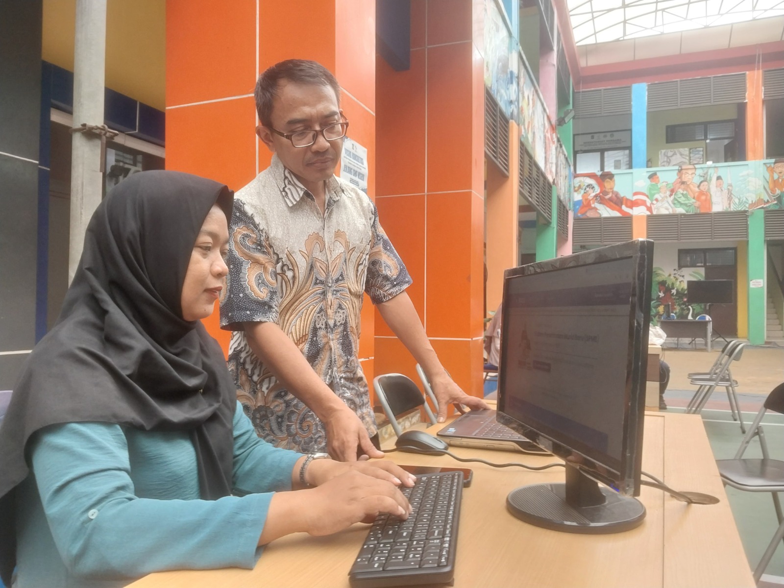 PANTAU PENDAFTARAN: Dua petugas Dispendik Surabaya mengakses situs SPMB SMP negeri jalur domisili.