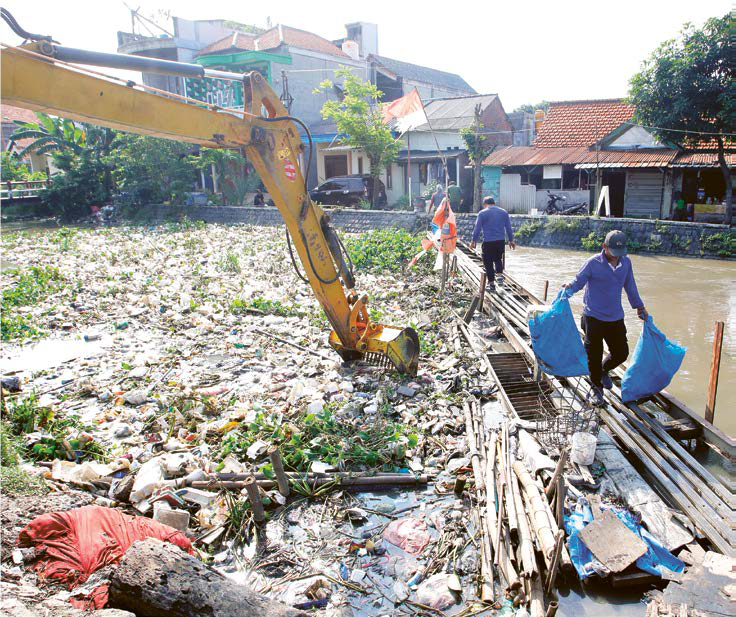 MENUMPUK: Petugas DPUBMSDA mengangkut sampah di Sungai Pelayaran Desa Krembangan kemarin (8/7).