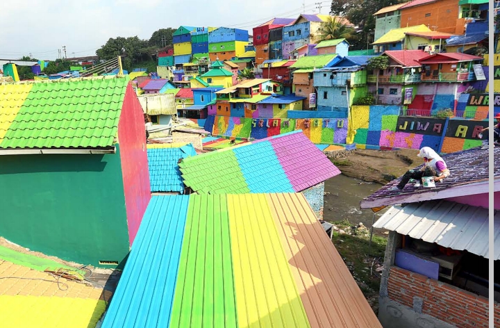 JADI CIRI KHAS: Para pekerja mengecat atap-atap rumah di Kampung Tridi yang berseberangan dengan Kampung Warna Warni kemarin (11/7). Pengecatan itu bisa dilakukan berkat bantuan CSR