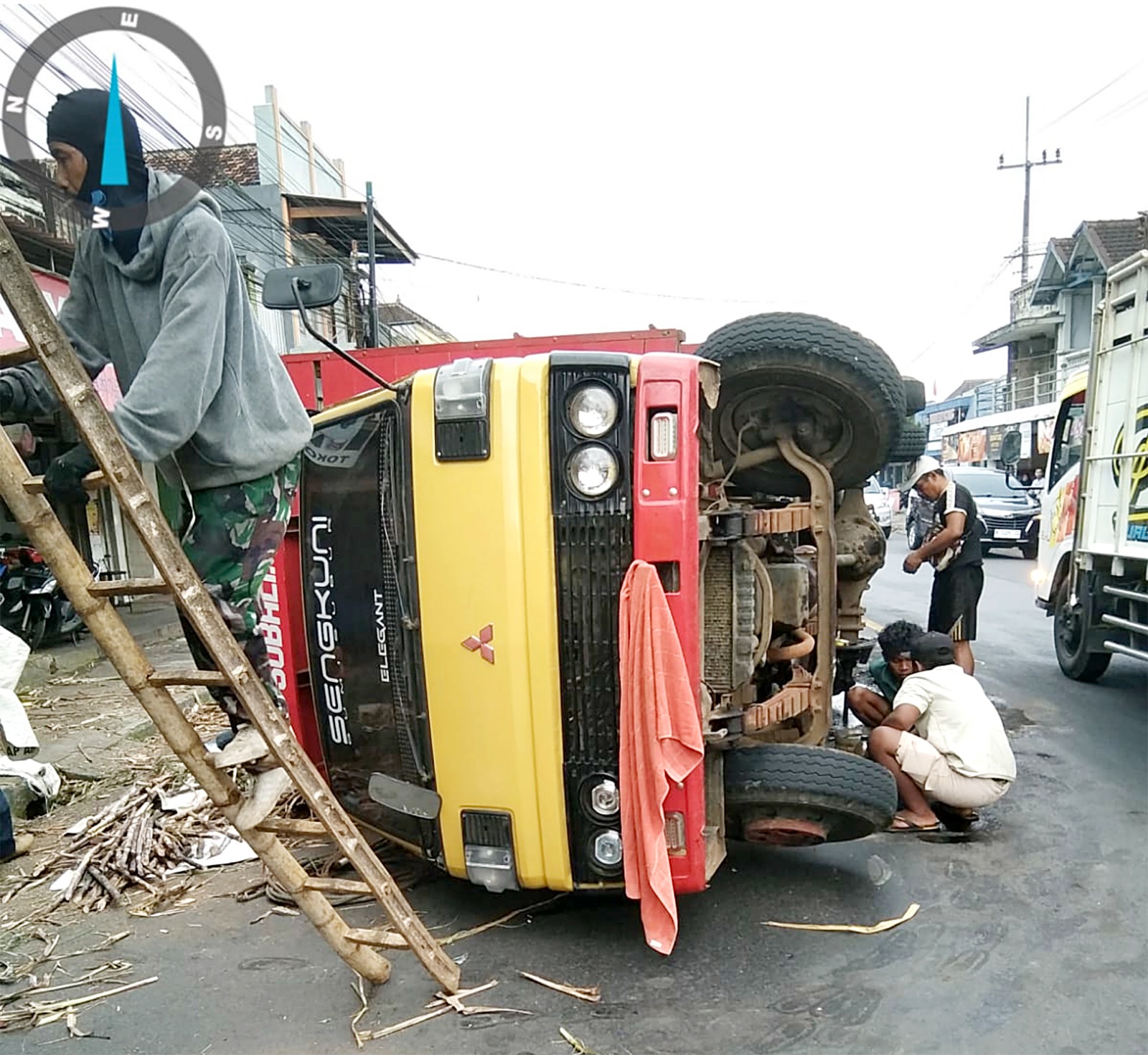BEARING JEBOL: Truk Mitsubishi Colt Diesel dengan nomor polisi N 8418 UG terguling di depan Pasar Sumberpucung, Minggu pagi (13/7). Diduga truk tersebut membawa muatan berlebih.