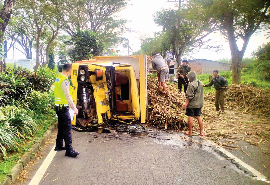 MENUTUP JALAN: Truk pengangkut tebu terguling setelah menabrak sebuah dump truck yang hendak putar balik di Jalan Lingkar Barat Kepanjen, kemarin (15/7).