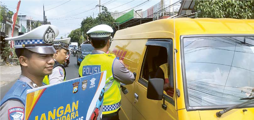 EDUKASI: Personel satlantas memampang papan imbau dalam Operasi Patuh Semeru di Dau kemarin.