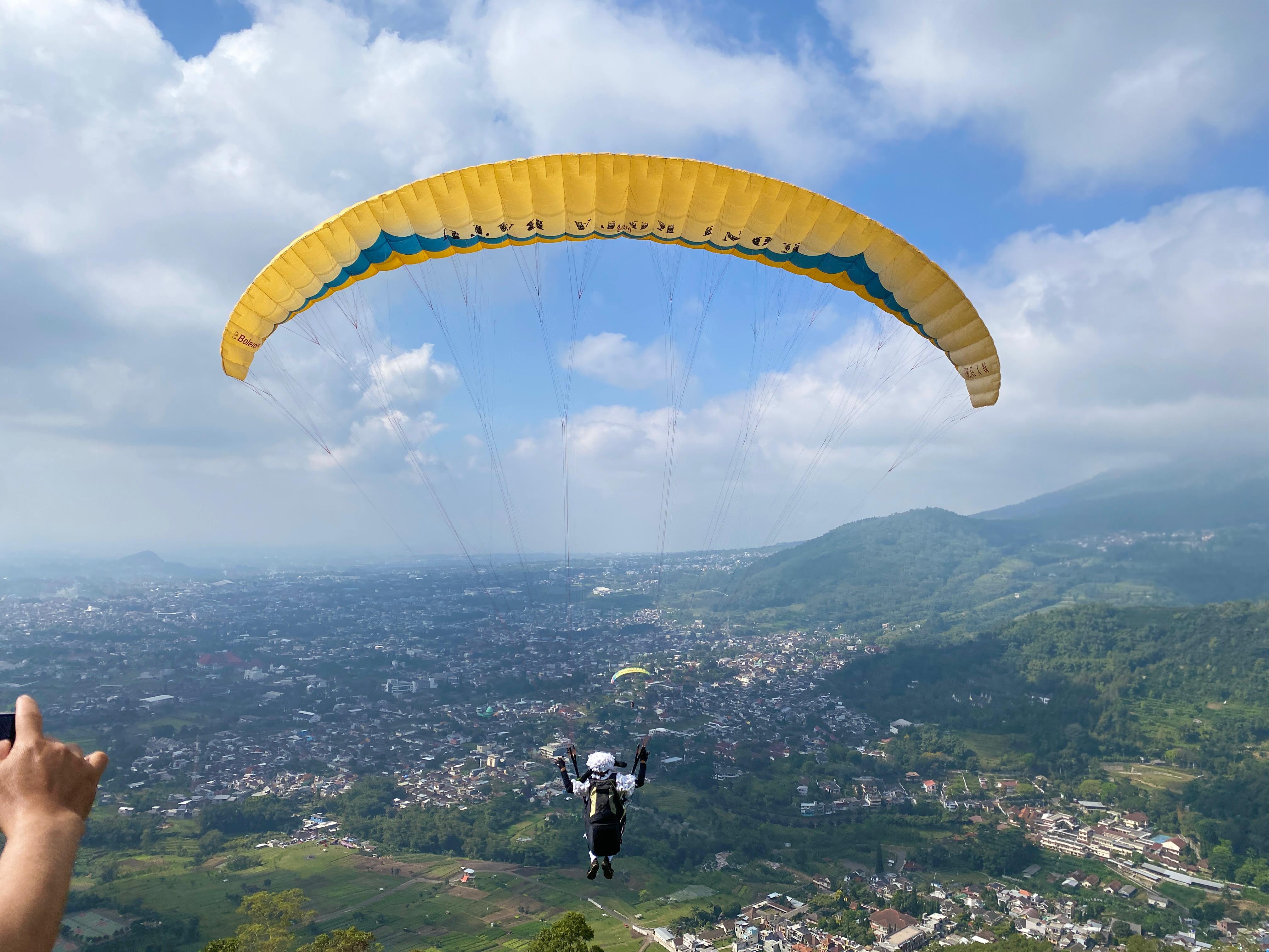 IKONIK: Salah seorang peserta Paragliding Accuracy League Batu International Sport Tourism Festival (BISTF) 2025 baru take off dari Gunung Banyak, Kota Batu kemarin pagi (18/7).
