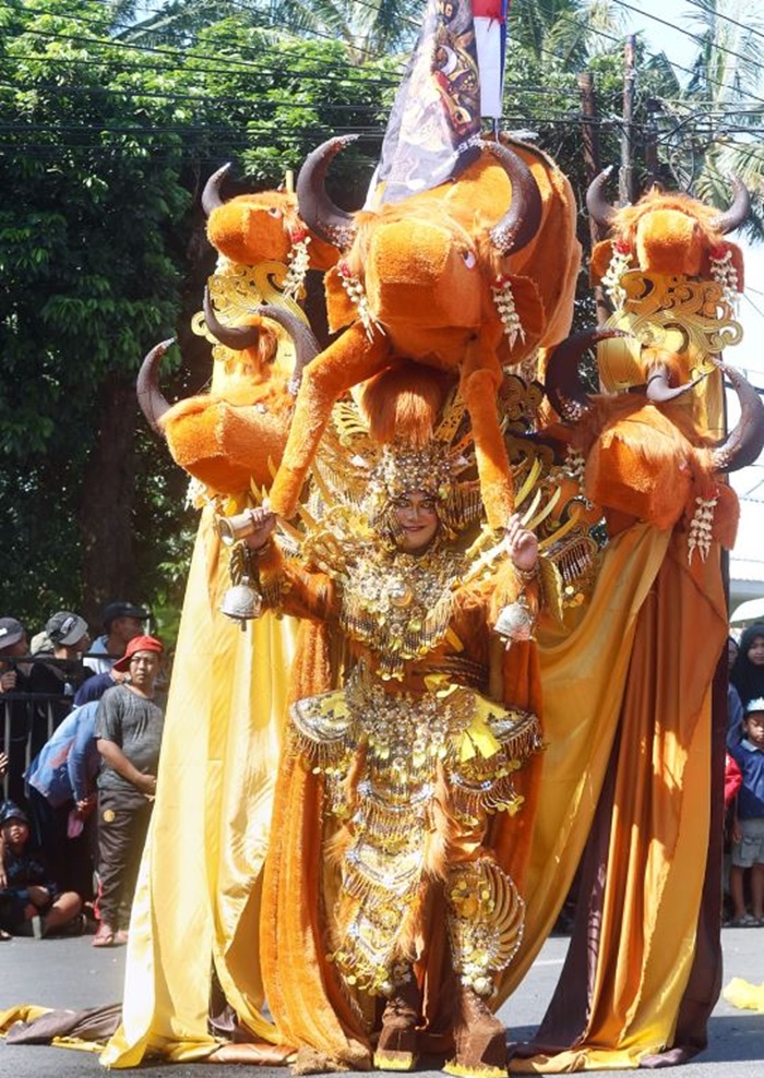 MENCOLOK: Salah satu peserta Kirab Budaya Cemorokandang 2025 menampilkan kostum setinggi 2,5 meter yang di atasnya diberi ornamen lima kepala banteng kemarin (20/7). Peserta lain menampilkan seni bant