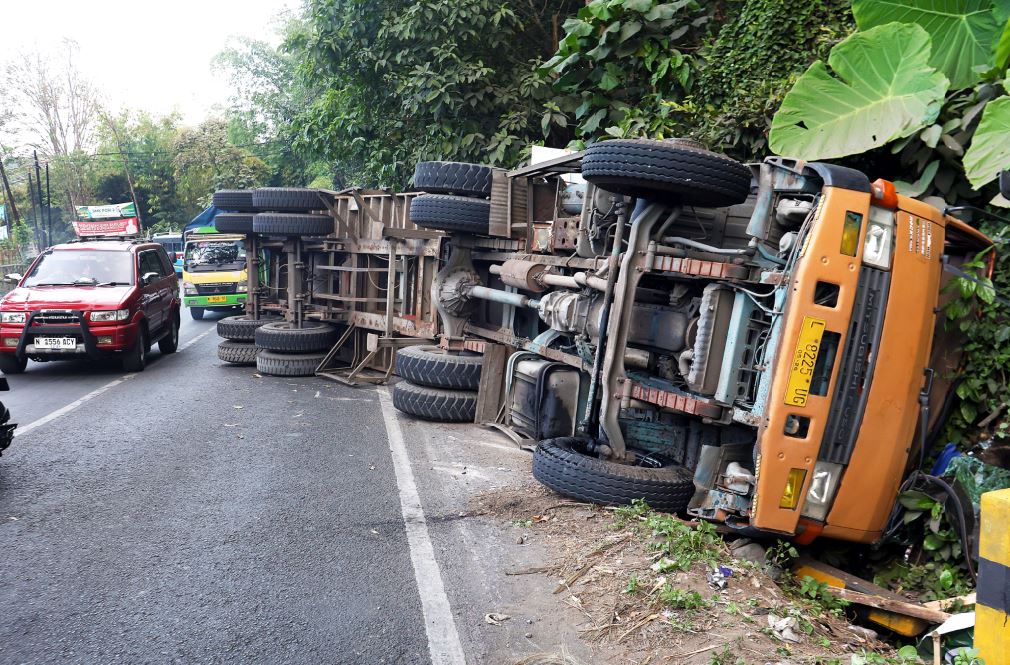 TITIK RAWAN: Truk pengangkut benih jagung seberat 21 ton untuk ekspor terguling di Jalan Raya Kendalpayak, Desa Kendalpayak, Kecamatan Pakisaji, Kabupaten Malang, kemarin siang (21/7). Truk itu gagal
