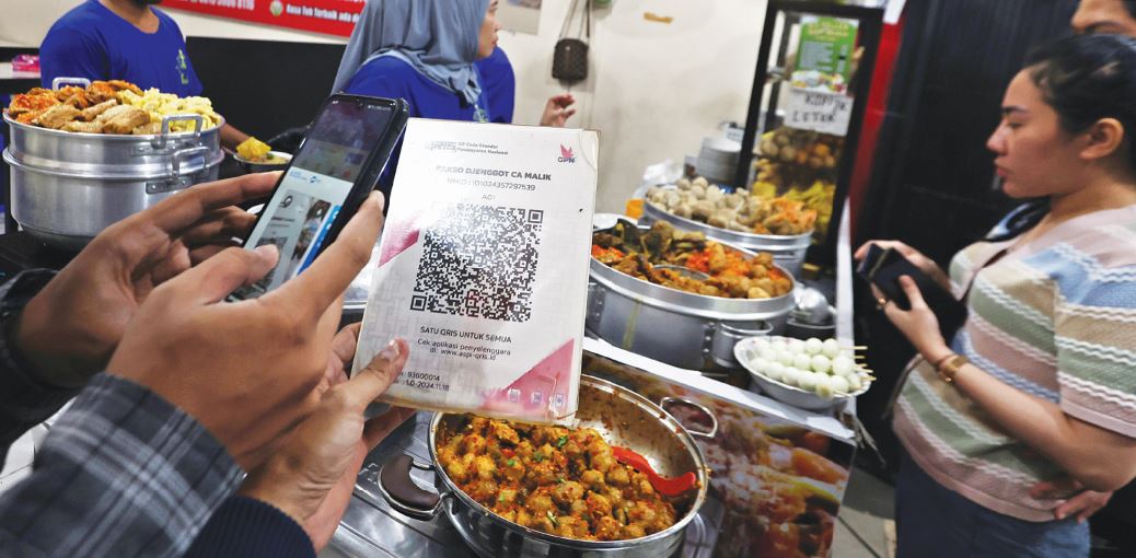 DIDOMINASI PELAKU UMKM: Salah satu pengunjung melakukan scan barcode QRIS untuk membayar makanan, kemarin.
