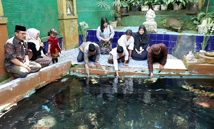 TRADISI: Warga melarung tiga pucuk tumpeng untuk memberi makan ikan di Sendang Widodaren yang terletak di dekat punden Mbah Kabul, kawasan New Wisata Wendit kemarin (24/7).