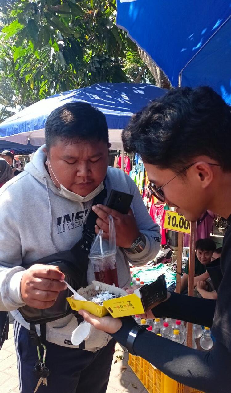 MENCOBA INOVASI TIWUL: Seorang pengunjung car free day mencoba sangtiwol rasa cokelat yang dijual di stan Museum Brawijaya.