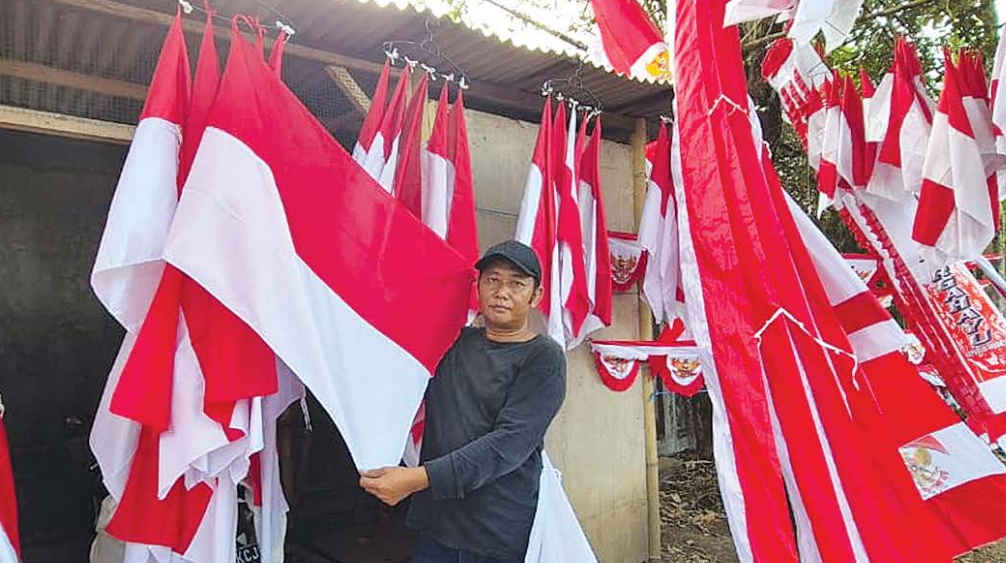 BERKAH KEMERDEKAAN: Sahlan Jannah berjualan bendera dan umbul-umbul merah putih di Jalan Panglima Sudirman, Kepanjen, kemarin (1/8).