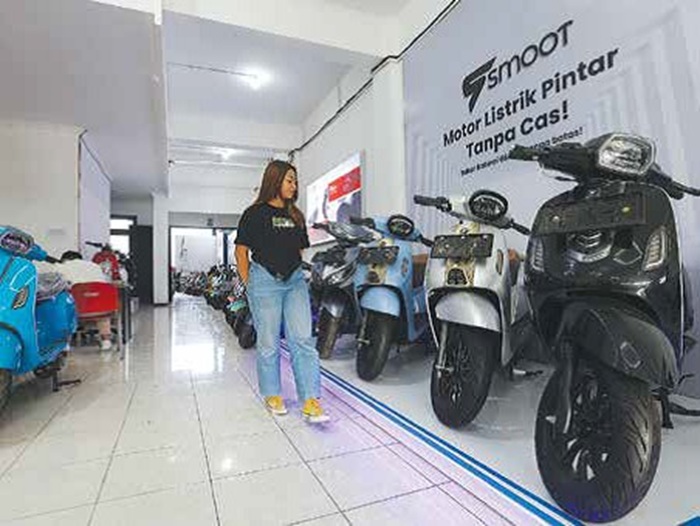 RAMAI PEMINAT: Seorang konsumen melihat deretan motor listrik di salah satu diler.