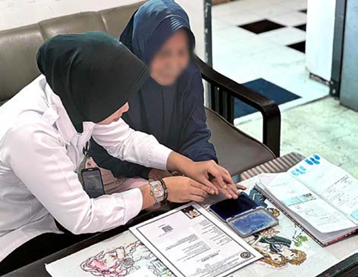 TANPA BIAYA: Warga binaan lansia berinisial J menandatangani surat penerimaan amnesti di LPP Kelas II A Malang kemarin (3/8).