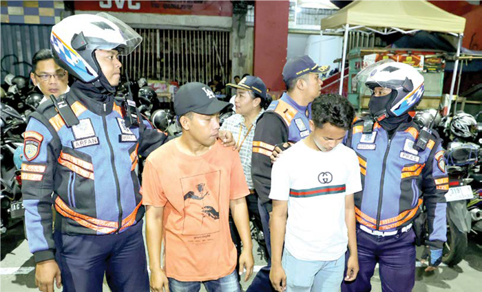 CEGAH PUNGLI: Petugas Dishub Surabaya Arfan (kiri) dan Pras menahan dua jukir ilegal di Jalan Tunjungan.