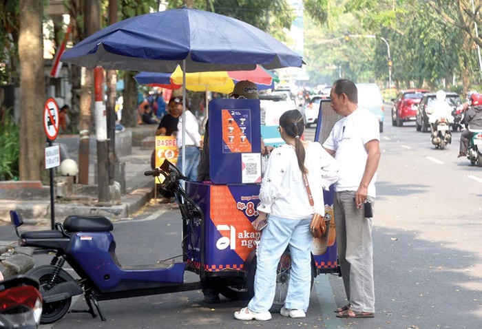 MENJAMUR: Dua konsumen membeli kopi keliling di Jalan Veteran kemarin siang. Pemkot bakal menata durasi mangkal para pedagang di sana.
