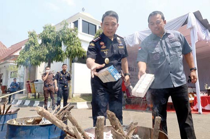 MUSNAHKAN ROKOK ILEGAL: Kepala Bea Cukai Kota Malang Johan Pandores (kiri) bersama staf Kejari Kota Malang membakar rokok ilegal kemarin (7/8).