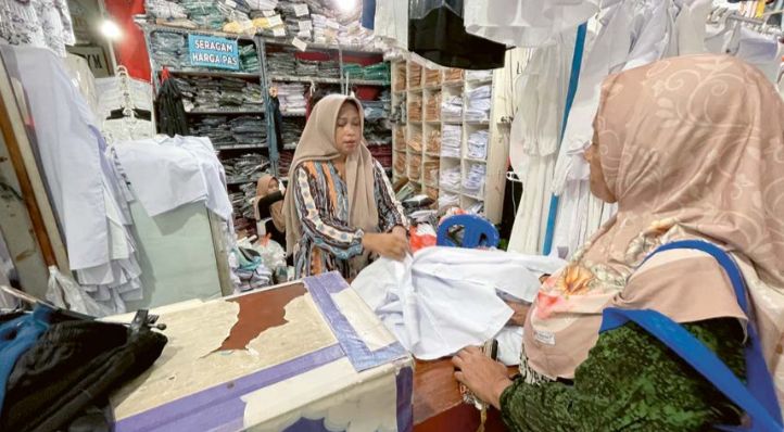 RUTINITAS TAHUNAN: Seorang pembeli memilih seragam di salah satu toko di Pasar Gresik. Di setiap tahun ajaran baru, omzet toko-toko seragam mengalami kenaikan.