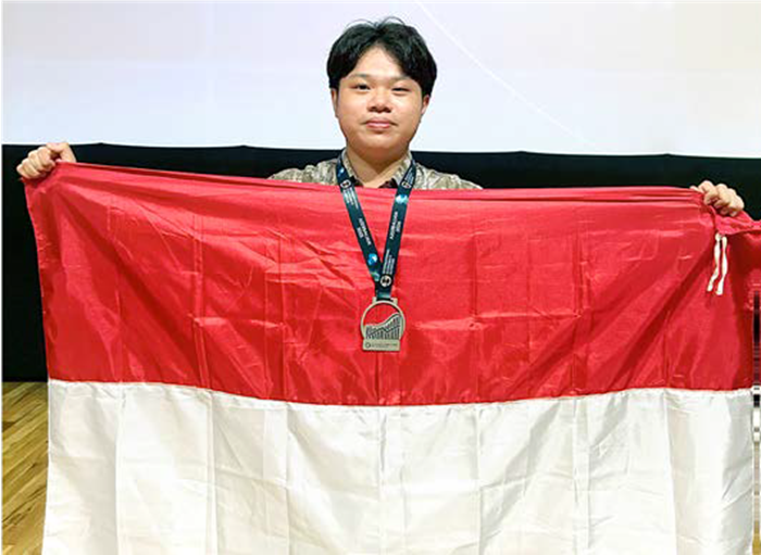 HARUMKAN NAMA INDONESIA: Panji Andika Saputra Wijaya membentangkan bendera merah putih setelah meraih medali perak di ajang International Economics Olympiad (IEO) 2025 di Azerbaijan, 30 Juli lalu.