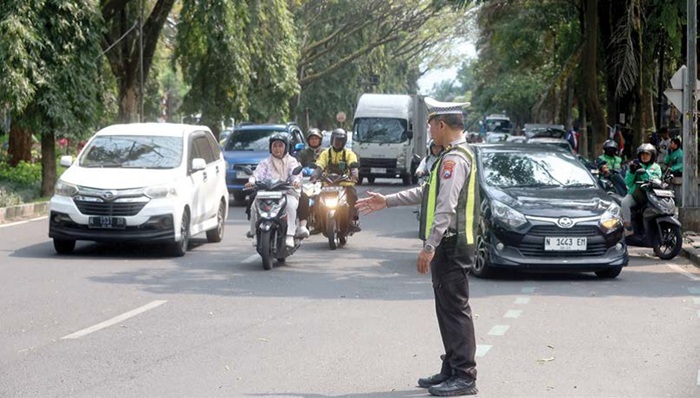 DIJAGA KETAT: Salah seorang personel Polresta Malang Kota sedang mengatur arus lalu lintas di Jalan Veteran, depan gerbang masuk BNI UB. Keberadaannya sekaligus untuk menertibkan parkir liar yang mara