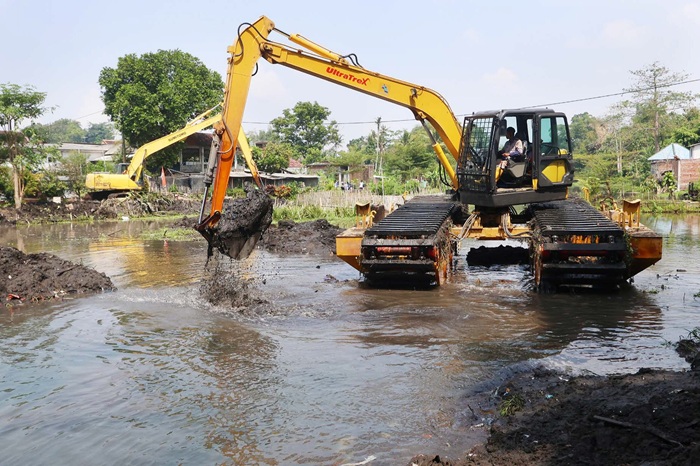DIKERJAKAN DUA BULAN: Salah satu ekskavator mengeruk sedimentasi dari aliran Sumber Wendit di Kecamatan Pakis, kemarin. Proses itu sudah dimulai Senin lalu (11/8).