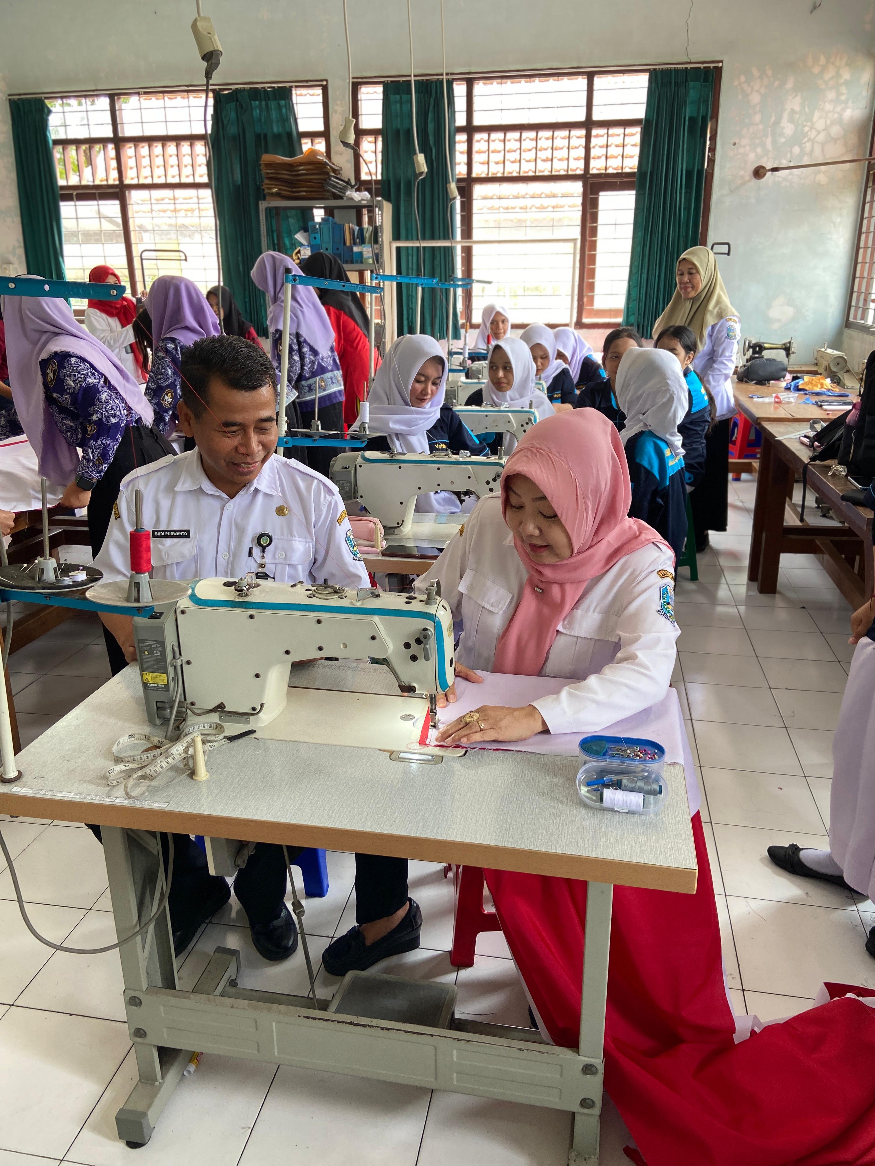 PANUTAN: Kepala Cabdindik Kota Malang - Kota Batu Dr Hj. Hastini Ratna Dewi MPd (kanan) bersama Kepala SMKN 5 Malang Budi Purwanto SPd MM (kiri) menjahit bendera merah putih yang akan memecahkan rekor