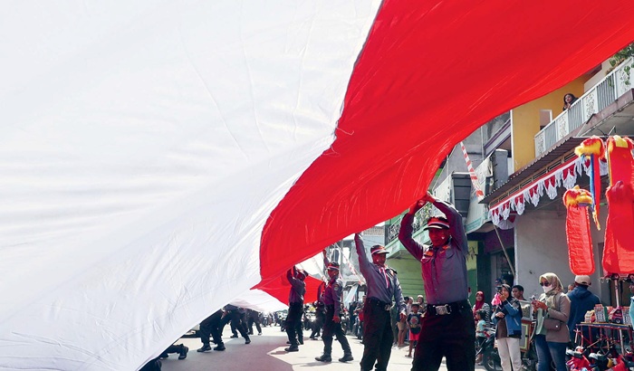 JIWA NASIONALISME: Personel linmas bersama warga membentangkan bendera merah putih di Jalan Rajasa, Bumiayu, Kecamatan Kedungkandang, Kota Malang kemarin (18/7). Bendera raksasa berukuran panjang 80 m