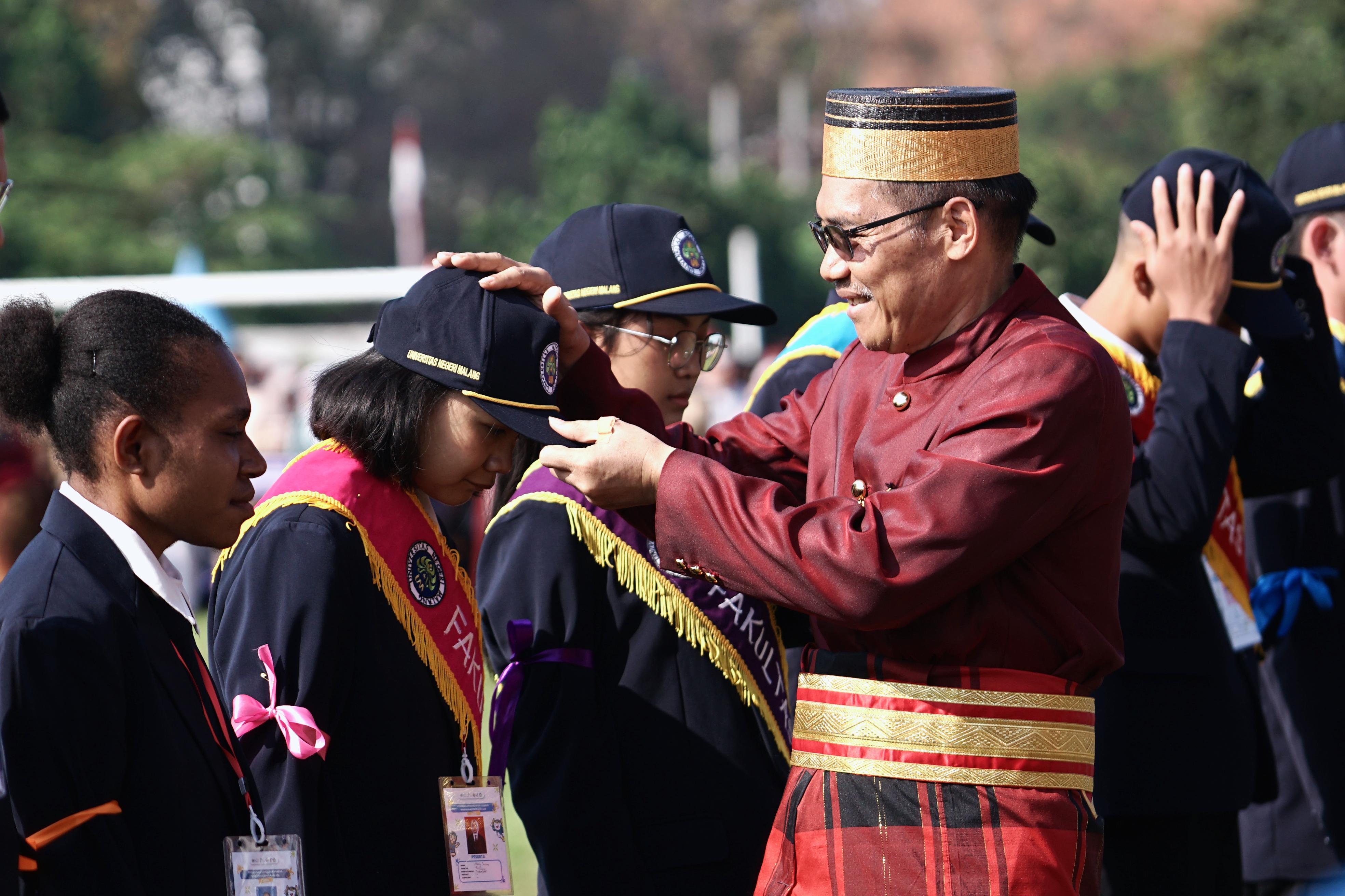 BERDAMPAK: Rektor UM Prof Hariyono MPd memasangkan topi dan selempang ke perwakilan maba dari 11 fakultas.