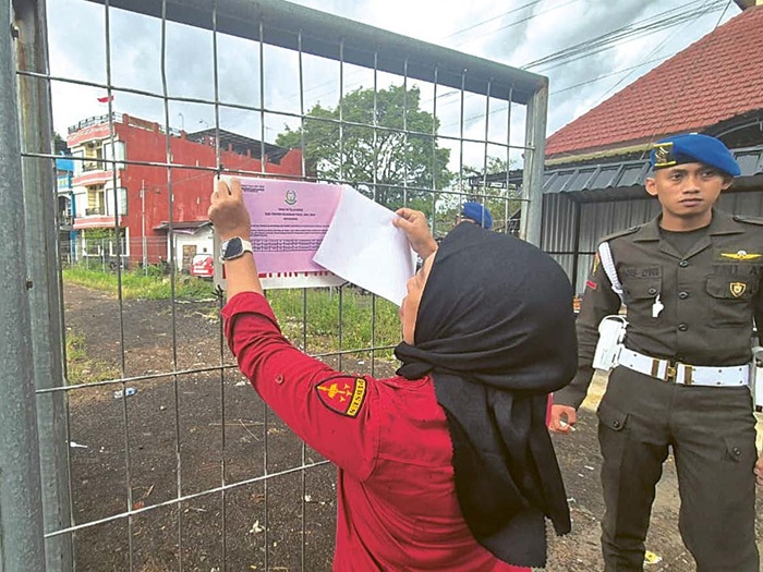 BARANG BUKTI: Kejaksaan Tinggi (Kejati) Jawa Timur memasang stiker penyitaan aset milik tersangka kasus korupsi pengadaan lahan Polinema pada Rabu (20/8).