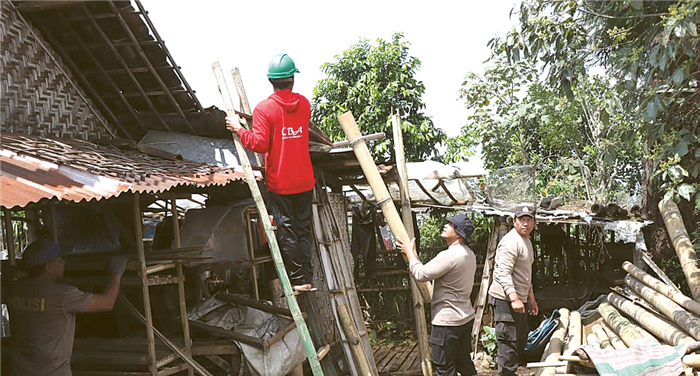 LANGSUNG TURUN TANGAN: Aparat kepolisian membantu membenahi rumah warga RT 11 RW 3 Dusun Biru, Desa Gunungrejo, Kecamatan Karangploso yang rusak akibat dilanda angin kencang kemarin.